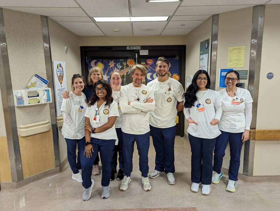 A group photo of bachelor's students in clinicals, wearing white and navy blue scrubs.