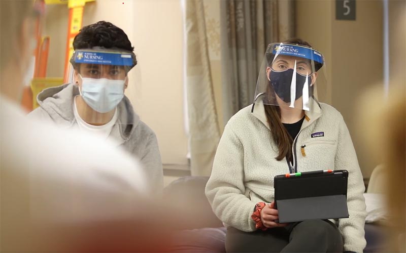 Students in the lab wearing PPE and using and iPad for learning