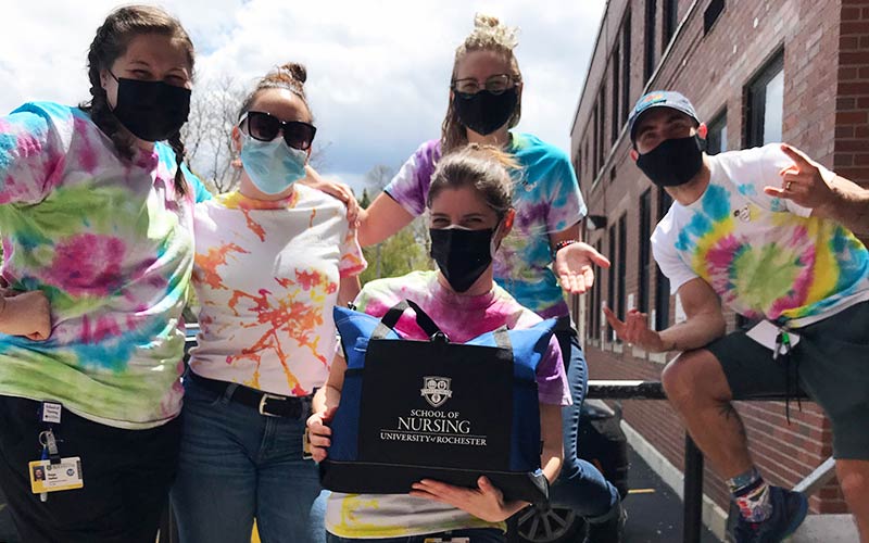 Students wearing tie-dye t-shirtds holding a School of Nursing duffle bag