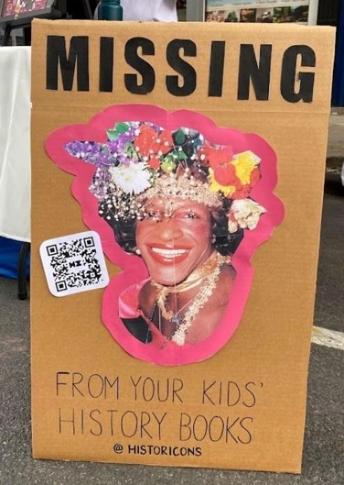 This poster was seen during the New York City Pride events this past June. It features an image of the Black transgender icon, Marsha P. Johnson, wearing a crown of flowers and smiling. Above her portrait are bold letters that say, “MISSING”, and underneath her image, the caption says, “From your kids’ history books.” The link listed on the bottom is for @historicons, a site that features historical games for children. 
