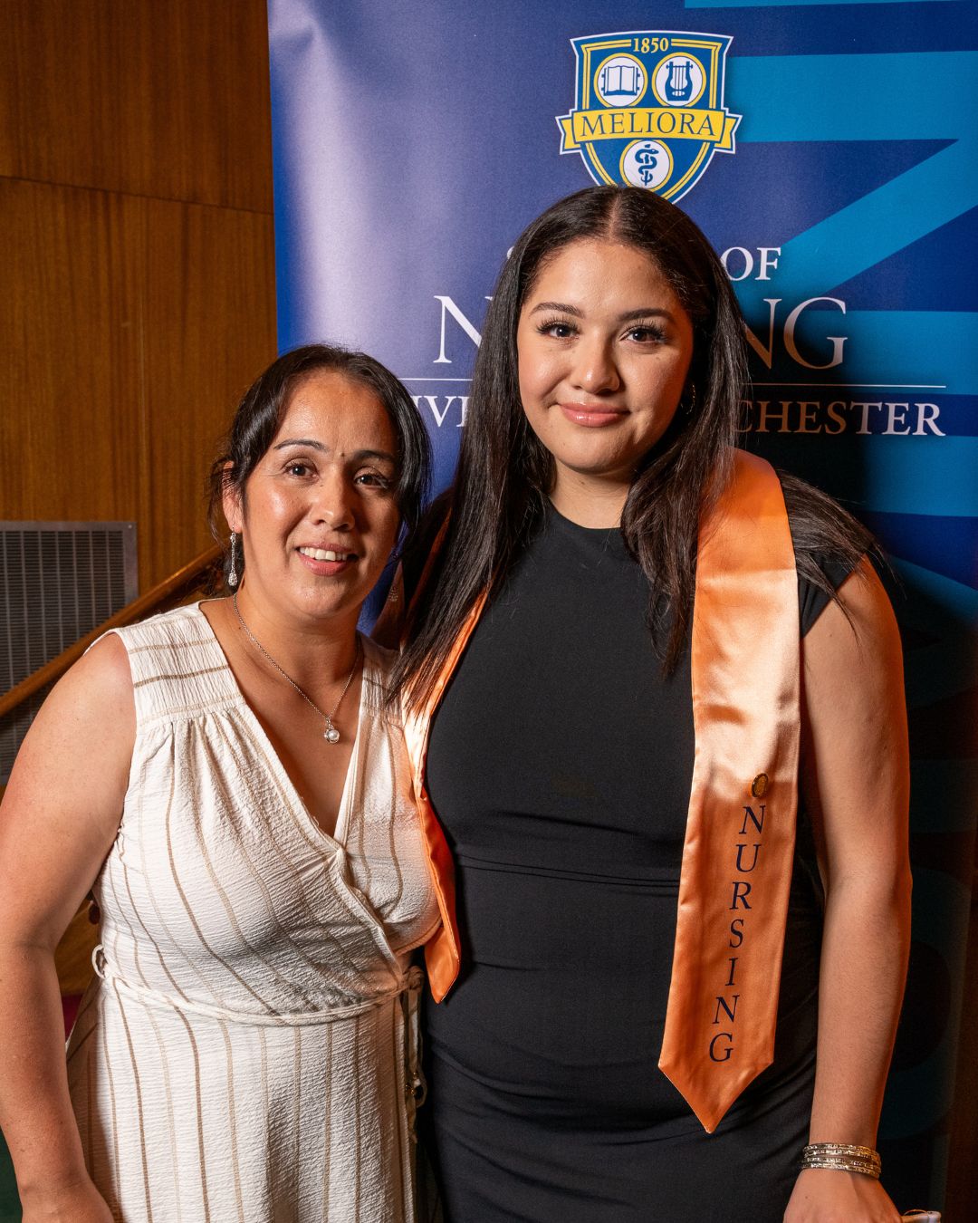 Arline poses for a photo at the pinning ceremony, wearing her pink nursing graduation sash.