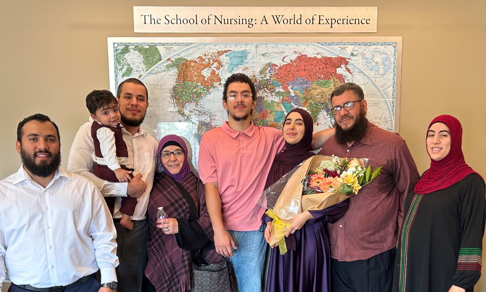 Nasreen Jaff and her family take a photo with a world map in the background.