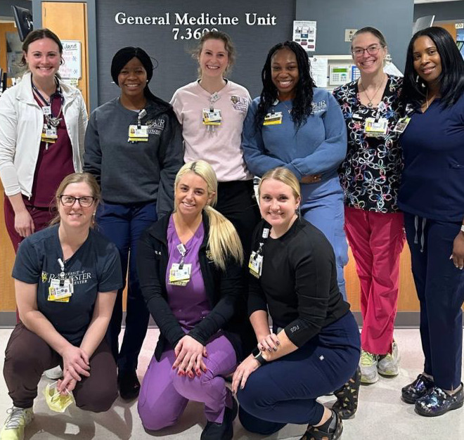 Group photo of URMC nurses with Sarah in the front middle row in purple scrubs.