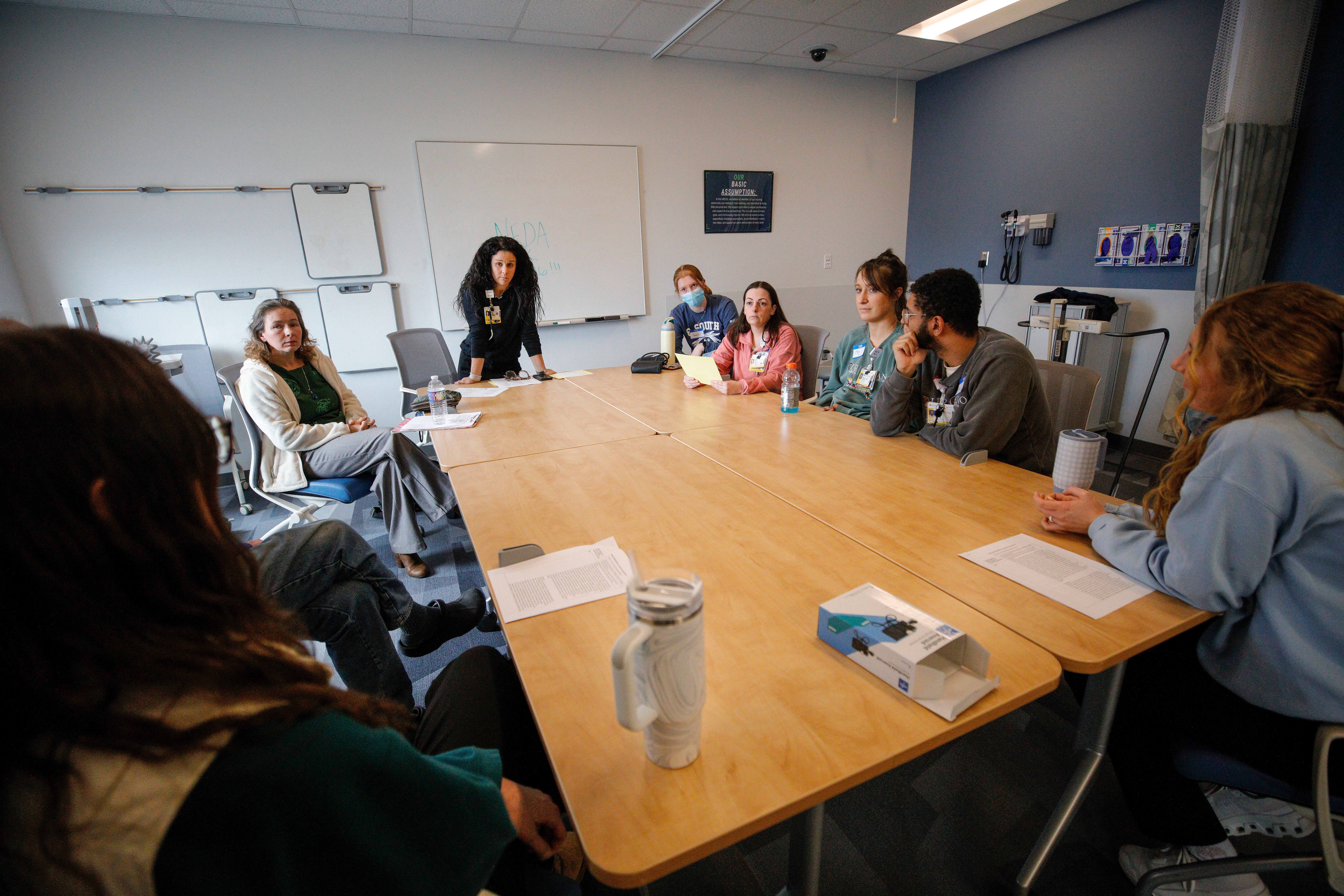 Participants in a simulation talk with a physician in a School of Nursing clinical classroom.