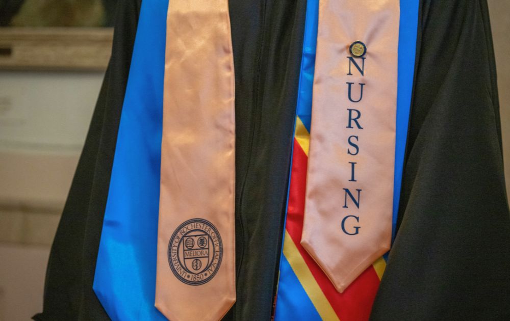 Close-up image of a graduation gown and nursing sash with gold pin