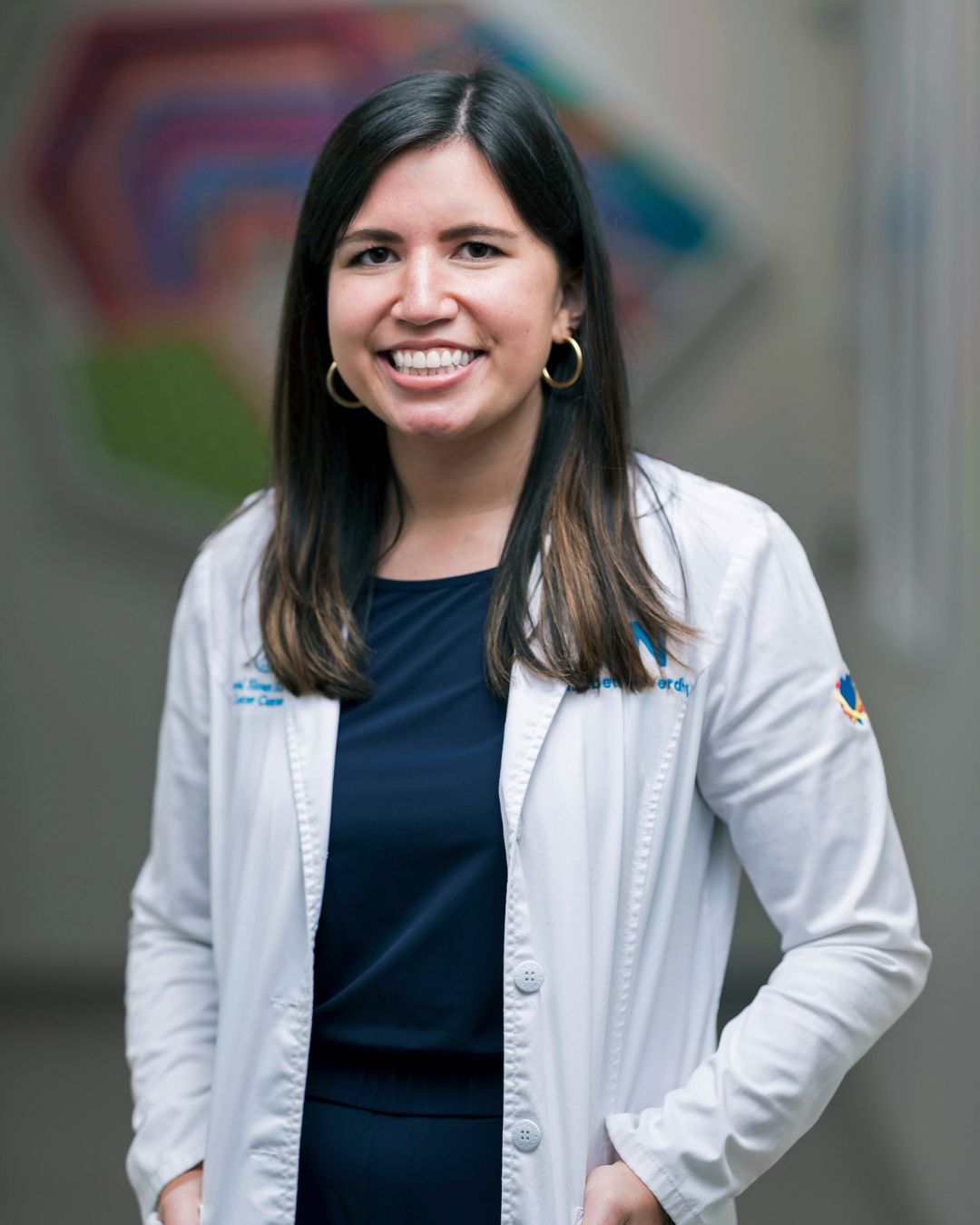 Headshot of Elizabeth standing in a hallway, wearing a white lab coat.